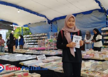 Seorang pengunjung telah menemukan buku yang akan dirinya beli dalam Bazar Buku di Halaman Gedung Layanan Perpustakaan Kabupaten Pacitan. (Foto: Diki Kurnia/Beritapacitan.com)