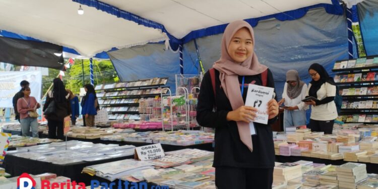 Seorang pengunjung telah menemukan buku yang akan dirinya beli dalam Bazar Buku di Halaman Gedung Layanan Perpustakaan Kabupaten Pacitan. (Foto: Diki Kurnia/Beritapacitan.com)