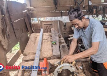 Seorang tukang mebel, Dawam (35), tengah fokus mengoperasikan mesin pemotong kayu di bengkel sederhananya yang terletak di kawasan Baleharjo, Pacitan. (Foto: Sunardi/Berita Pacitan).