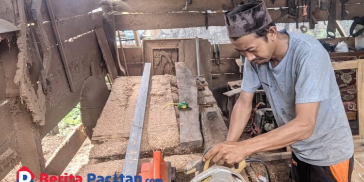 Seorang tukang mebel, Dawam (35), tengah fokus mengoperasikan mesin pemotong kayu di bengkel sederhananya yang terletak di kawasan Baleharjo, Pacitan. (Foto: Sunardi/Berita Pacitan).