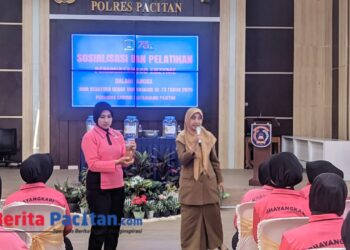 Dengan memegang botol hasil fermentasi, salah satu peserta Bhayangkari mendampingi Kepala DLH Pacitan Cicik Roudlotul Jannah yang memberikan pemaparan manfaat eco-enzyme di hadapan puluhan anggota Bhayangkari, Senin, 30 Juni 2025. (Foto: Sunardi Berita Pacitan)