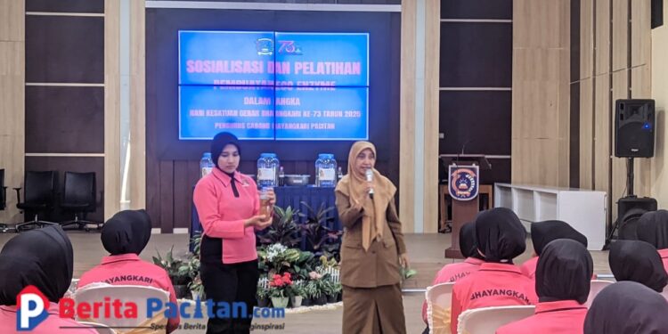 Dengan memegang botol hasil fermentasi, salah satu peserta Bhayangkari mendampingi Kepala DLH Pacitan Cicik Roudlotul Jannah yang memberikan pemaparan manfaat eco-enzyme di hadapan puluhan anggota Bhayangkari, Senin, 30 Juni 2025. (Foto: Sunardi Berita Pacitan)