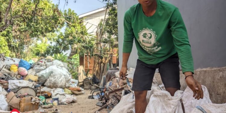 Indra, pekerja harian pemilah rongsokan di Ploso, Pacitan. Meski kerja keras seharian, penghasilan yang didapat sering kali tak cukup untuk menutup kebutuhan rumah tangga.” (foto: Sunardi/Berita Pacitan)