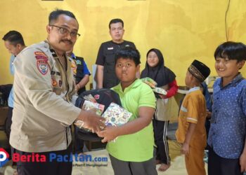 Bhabinkamtibmas Polsek Pacitan, Aipda Latip Utomo, menyerahkan bantuan perlengkapan sekolah kepada salah satu anak di Desa Kalikuning dalam kegiatan sosial yang digelar LSM Kalikuning Sigap Bersinergi (KSB). (Foto : Sunardi Berita Pacitan).