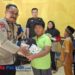 Bhabinkamtibmas Polsek Pacitan, Aipda Latip Utomo, menyerahkan bantuan perlengkapan sekolah kepada salah satu anak di Desa Kalikuning dalam kegiatan sosial yang digelar LSM Kalikuning Sigap Bersinergi (KSB). (Foto : Sunardi Berita Pacitan).