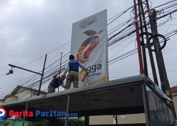 Petugas Satpol PP Pacitan saat menurunkan salah satu reklame tidak berizin dalam rangkaian penertiban di wilayah kota. (Foto: Sunardi/Berita Pacitan).