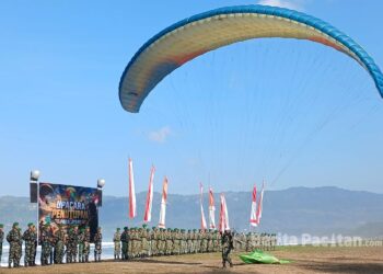 Prajurit Yonif Teritorial Pembangunan (TP) 934/Satria Buwana Yudha menampilkan demonstrasi paralayang saat upacara penutupan latihan paralayang di kawasan Pantai Pancer Door, Pacitan. (Foto: Sunardi / BeritaPacitan.com).